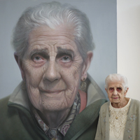 Photograph of Ivy stood in front of large portrait painting of herself