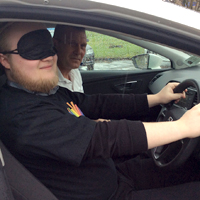 Photograph of driver at wheel with blindfold on