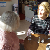 Photo of two people chatting over a drink