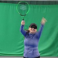 Photo of Janiece serving at tennis