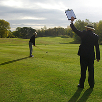 Photo of two people on the golf course one is teeing off