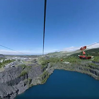 Photo of someone doing the zip line over a blue coloured lake