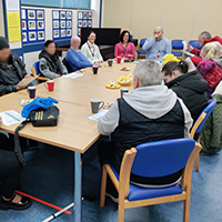 Photo of some people sat around a table in a previous group