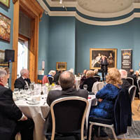 Photo of guests sitting at tables listening to one of the speakers