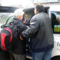 Photograph of a taxi driver assisting someone into a taxi