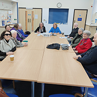 Photo of some people sat around a table in the meeting