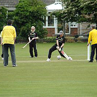 Photograph of people playing cricket outdoors