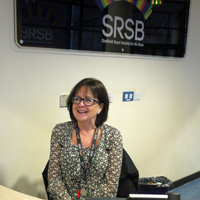 Photograph of Carol sat behind the reception desk