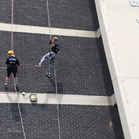 Photo of two people abseiling down the Owen Building