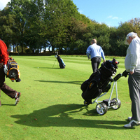 Photo of people on a golf course with trolleys