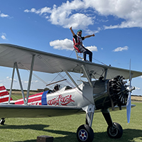 Photo of someone on top of a small plane with their arms outstretched 