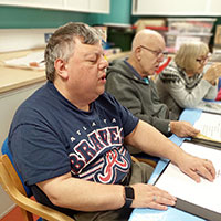 Photo of volunteer singing and reading braille music