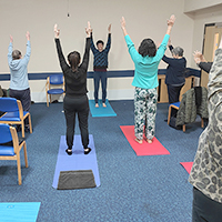 Photo of some people in a yoga session with their arms in the air